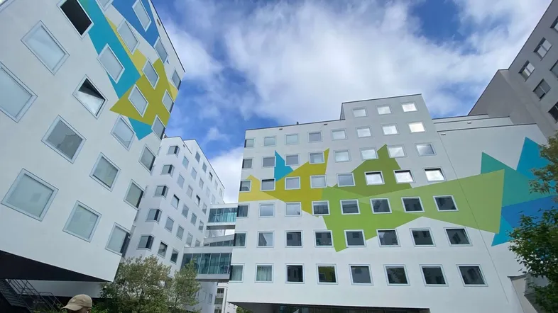 Moderne Gebäude mit farbenfrohen geometrischen Fassaden und vielen Fenstern unter blauem Himmel.
