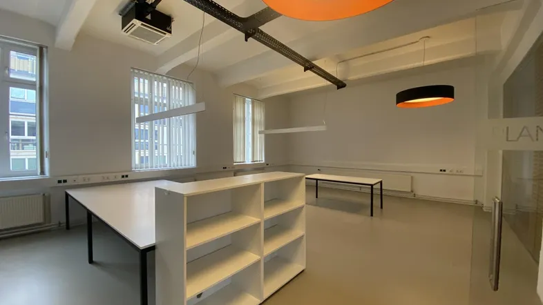 Heller und geräumiger Büroraum mit hohen Decken, großen Fenstern und modernen Leuchten.