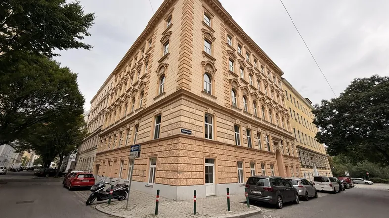 Historisches Eckgebäude mit aufwendiger Fassadengestaltung und vielen Fenstern an einer städtischen Straße.