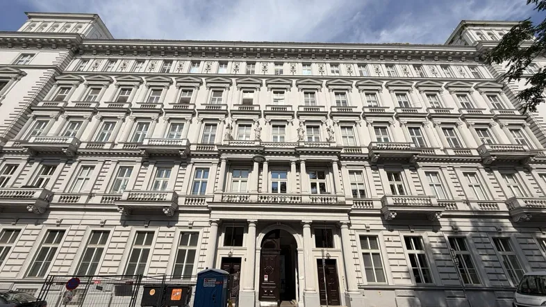 Klassisches Gebäude mit reich verzierter Fassade, vielen Fenstern und Balkonen unter blauem Himmel.