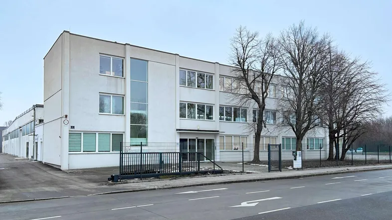 Ansicht des modernen Büro- und Lagergebäudes von der Straße aus mit Bäumen und Parkplätzen.