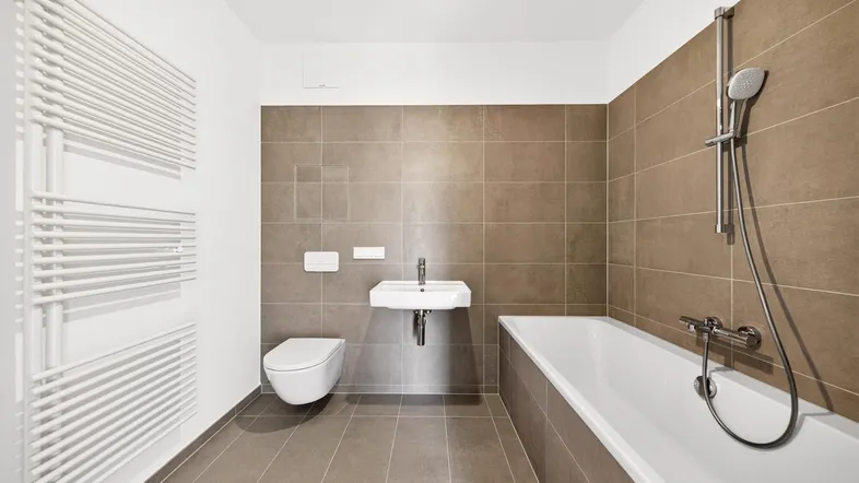 Modernes Badezimmer mit braunen Fliesen, Badewanne, WC und beheiztem Handtuchhalter.