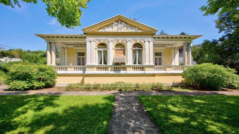 Elegante Villa im klassischen Stil mit gepflegtem Vorgarten und sonnigem Ambiente.