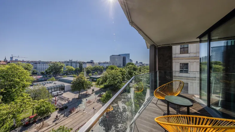 Heller Balkon mit modernen Sitzgelegenheiten und weitem Blick über die Stadtlandschaft.