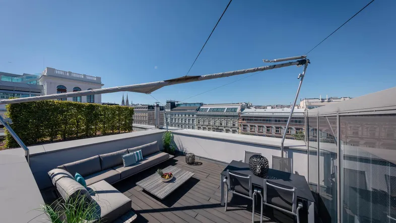 Geräumige Dachterrasse mit bequemen Loungemöbeln und Esstisch, bietet einen weiten Stadtblick.
