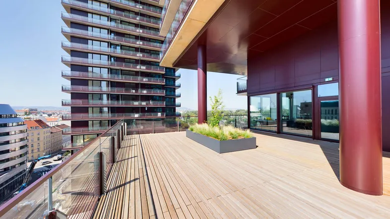 Geräumige Holzterrasse mit Glasgeländer und Blick auf die Stadt, umgeben von moderner Hochhausarchitektur.