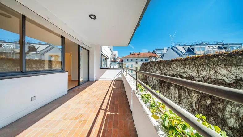Langer Balkon mit Terrakottafliesen und einer begrünten Wand, der einen Blick auf die Umgebung bietet.
