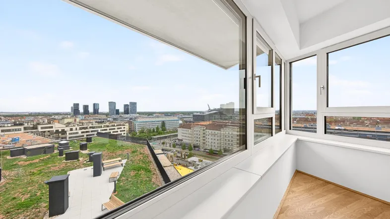 Heller Innenraum mit großen Fenstern und weitem Blick über die Stadt und begrünte Dächer.