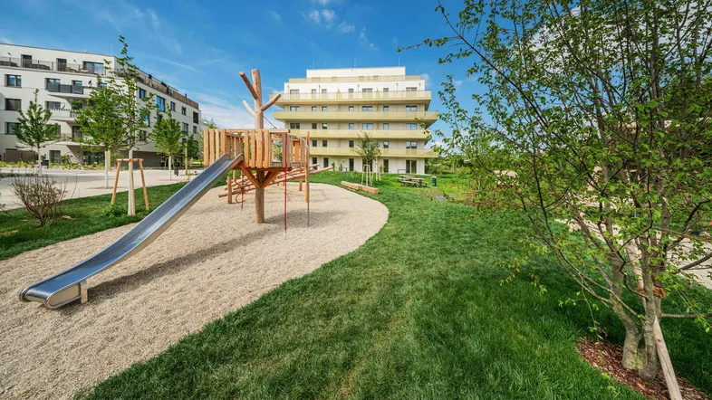 Moderner Wohnkomplex mit großzügiger Grünfläche und Kinderspielplatz im Freien.