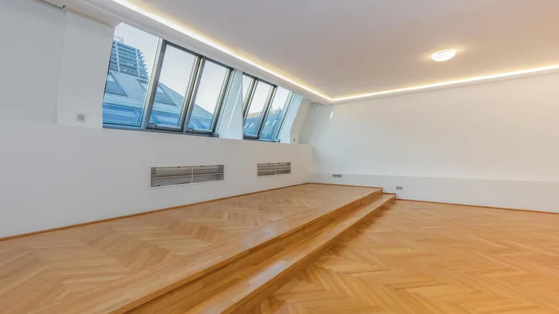 Helles, modernes Zimmer mit Dachschrägenfenstern, Holzparkettboden und indirekter Deckenbeleuchtung.