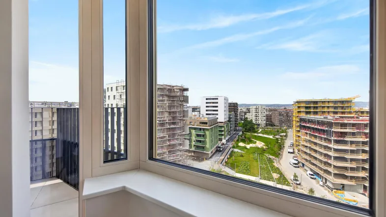 Heller Innenraum mit großem Fenster und weitem Blick auf die umliegende Stadtbebauung.