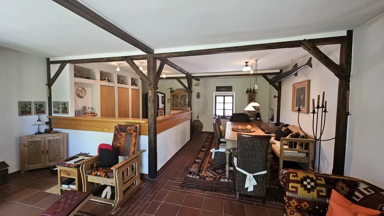 Rustikaler offener Wohn- und Essbereich mit Holzbalken, Terrakottaboden und traditionellen Möbeln.