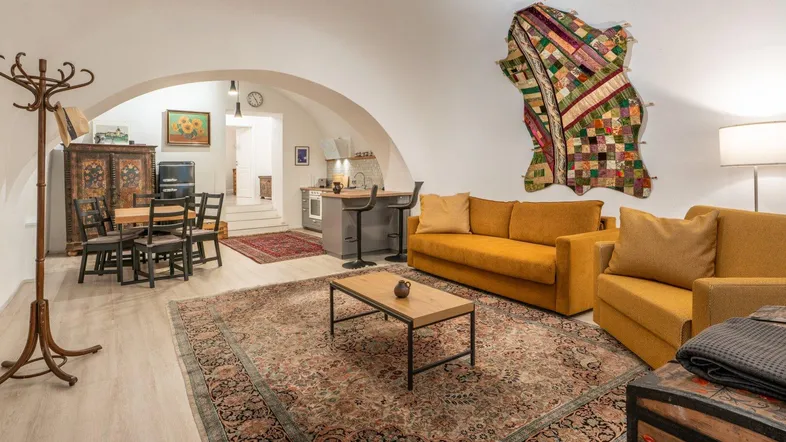 Geräumiger Wohn- und Essbereich mit bequemen Sofas, Esstisch und Zugang zur Küche unter gewölbten Decken.