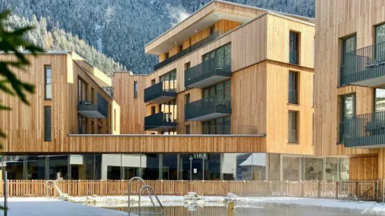 Moderne Holzfassaden-Gebäude mit Außenpool und beeindruckendem Alpenpanorama im winterlichen Ambiente.