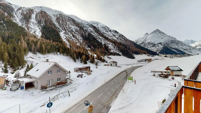 Panoramablick auf die verschneite Berglandschaft mit Häusern und einer Straße im Winter.