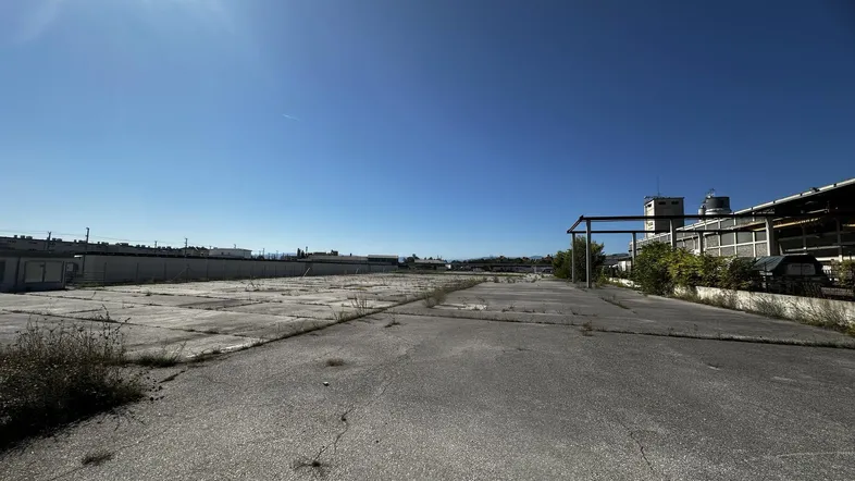 Große, gepflasterte Fläche mit einem Industriegebäude im Hintergrund unter strahlend blauem Himmel.