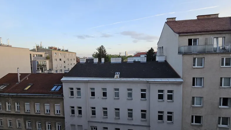Blick über Dächer und umliegende Gebäude in einer städtischen Umgebung bei hellem Himmel.