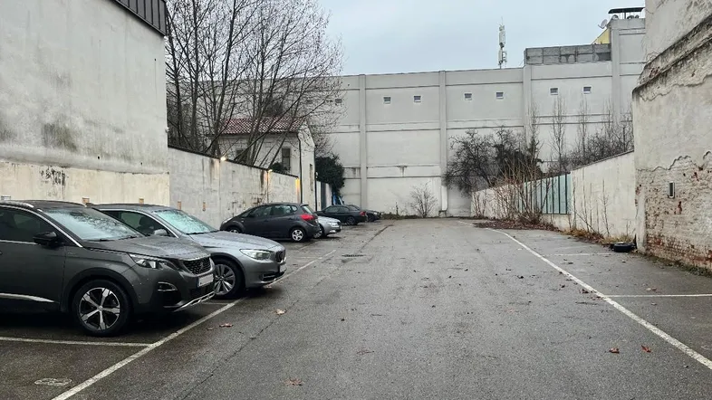 Außenbereich mit Parkplätzen und umliegenden Gebäuden an einem bewölkten Tag.