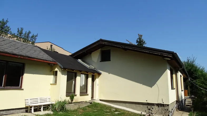 Seitenansicht des Hauses mit heller Fassade und einem kleinen Gartenbereich.