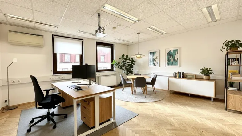 Modern eingerichtetes Büro mit Schreibtisch, Besprechungsbereich und Fischgrätparkettboden.