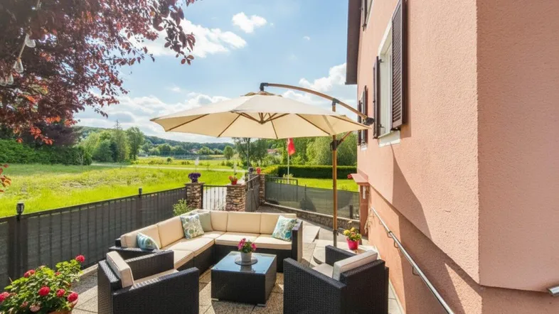 Gemütliche Terrasse mit Loungemöbeln und weitem Blick ins Grüne unter blauem Himmel.