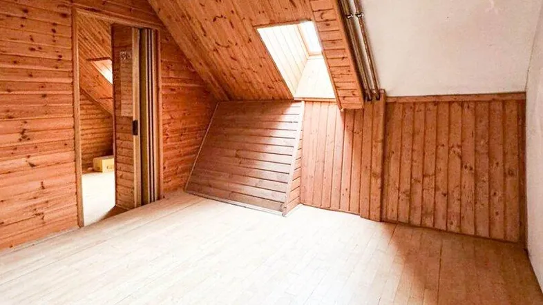 Heller Dachbodenraum mit Holzverkleidung, Schrägdach und Dachfenster, ideal als Wohnraum.
