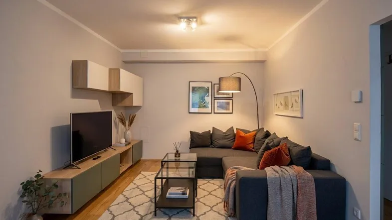 Modernes Wohnzimmer mit bequemer Eckcouch, TV-Möbeln und Holzboden.