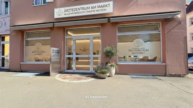 Fassade eines Ärztezentrums mit großen Schaufenstern und Eingangsbereich, umgeben von Topfpflanzen.