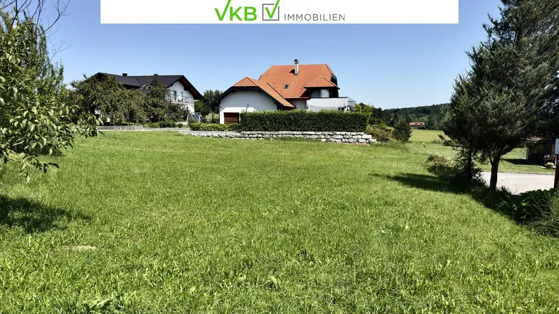 Weitläufige Grünfläche mit Blick auf umliegende Häuser und die ländliche Umgebung unter blauem Himmel.