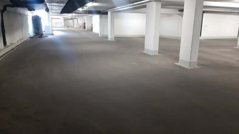 Geräumige Tiefgarage mit Betonboden und weißen Säulen, ideal für das Parken mehrerer Fahrzeuge.