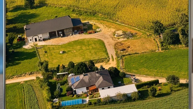 Luftaufnahme eines Anwesens mit Wohnhaus, Nebengebäude, Feldern und einem Swimmingpool in ländlicher Umgebung.