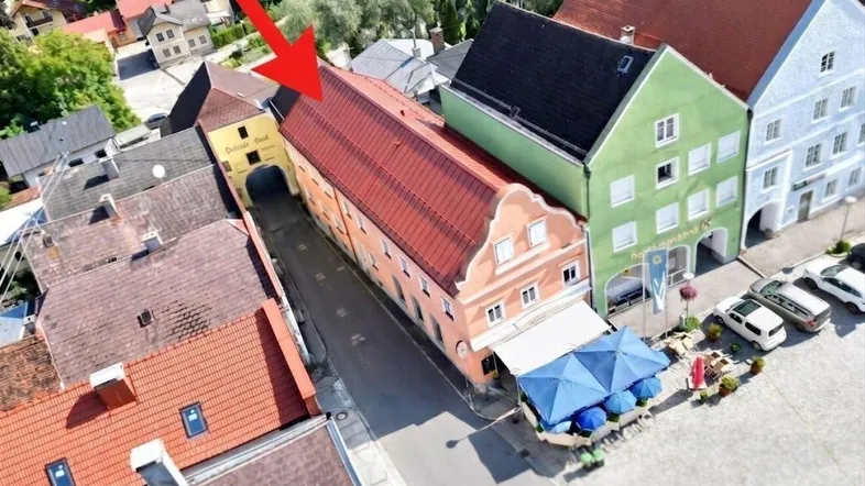 Luftaufnahme einer historischen Gasse mit farbenfrohen Gebäuden und einem Restaurant mit Außenterrasse.