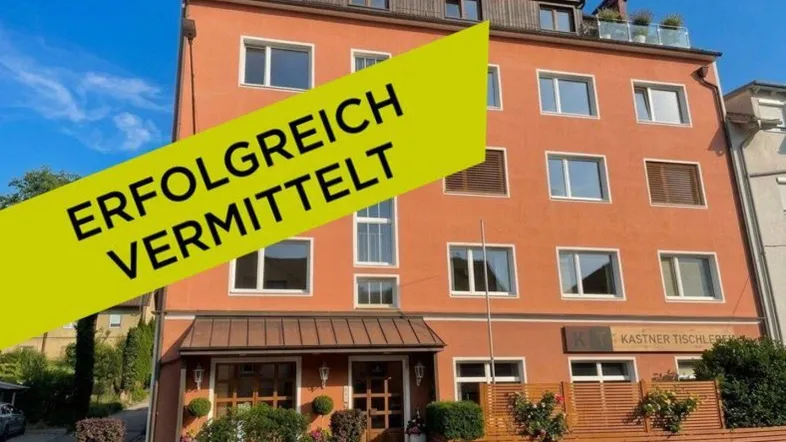 Mehrstöckiges Gebäude mit oranger Fassade, vielen Fenstern und einer Dachterrasse.