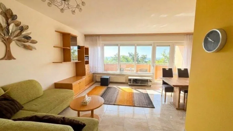 Heller Wohn- und Essbereich mit Fliesenboden, bequemer Couch und Esstisch, bietet einen weiten Ausblick.