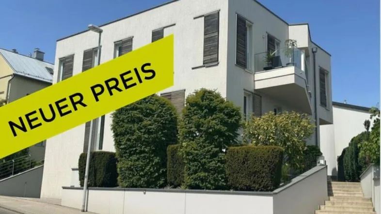 Modernes Mehrfamilienhaus mit weißer Fassade, Holzfensterläden und einem Balkon mit Glasgeländer.