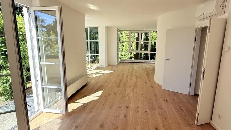 Helles, geräumiges Wohnzimmer mit Eichenparkettboden und großen Fenstern mit Blick ins Grüne.