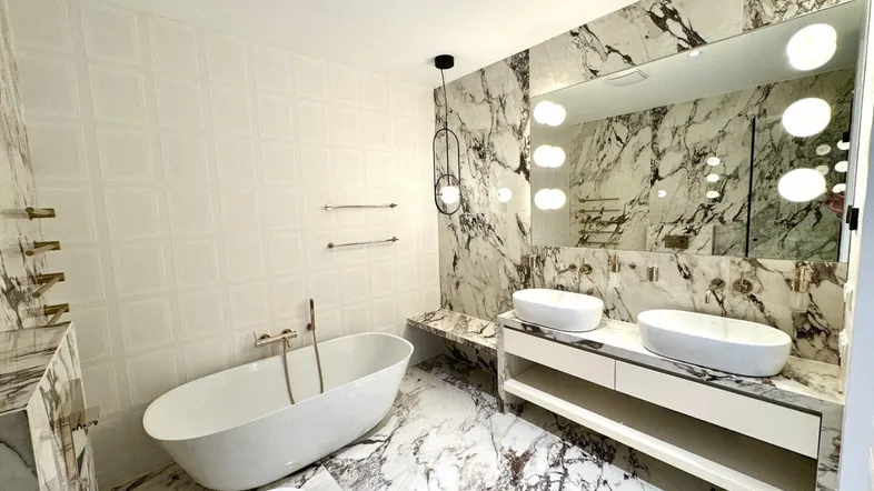 Luxuriöses Badezimmer mit freistehender Badewanne, Doppelwaschbecken und eleganten Marmorfliesen.