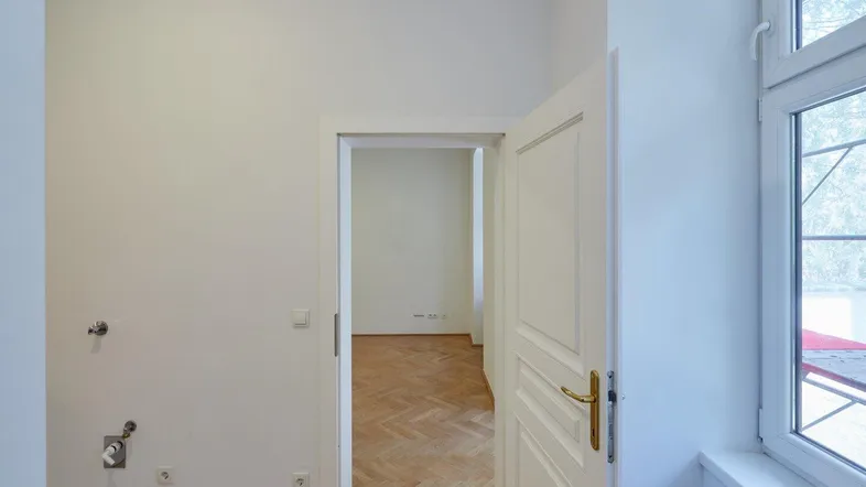 Helle Diele mit Parkettboden und Zugang zu weiteren Räumen, gut beleuchtet durch ein Fenster.