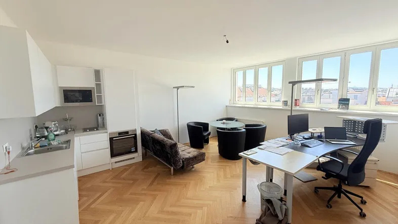 Helles, offenes Büro mit integrierter Küchenzeile, Parkettboden und weitem Blick über die Stadt.