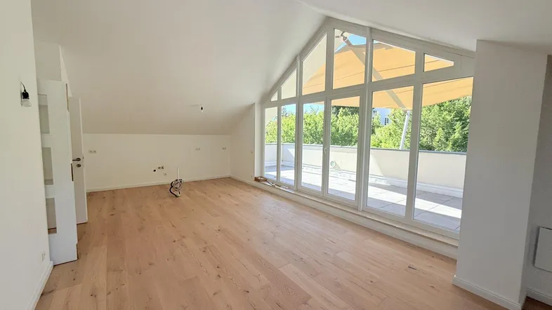Helles, geräumiges Zimmer mit Holzboden, hohen Fenstern und Zugang zu einer Terrasse.