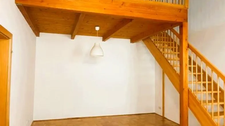 Heller Raum mit Holz-Empore und Treppe, ausgestattet mit Parkettboden und weißen Wänden.