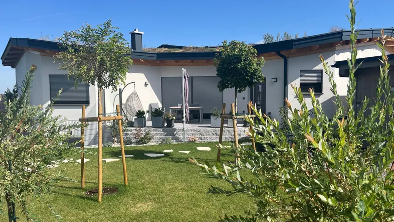 Modernes Haus mit Gründach, gepflegtem Garten und einer gemütlichen Terrasse mit Sitzgelegenheiten.