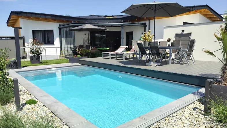 Moderner Außenbereich mit großem Pool, Holzterrasse und Gartenmöbeln unter Sonnenschirmen.