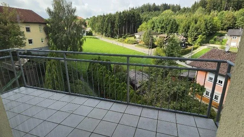 Geräumiger Balkon mit Fliesenboden und weitem Blick ins Grüne und auf die umliegende Landschaft.