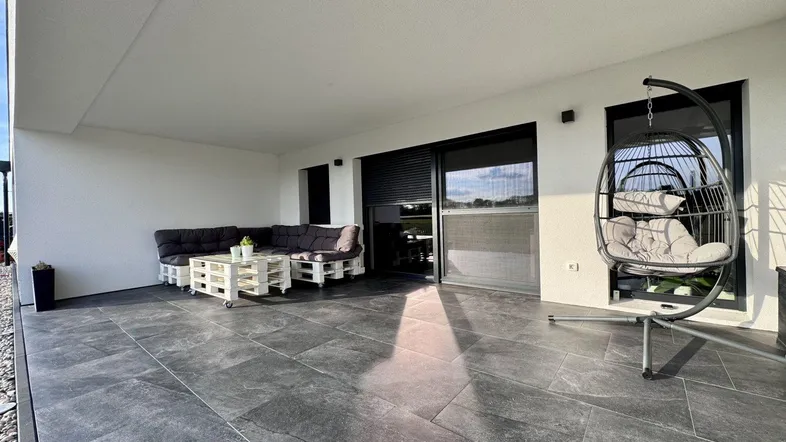 Große, geflieste Terrasse mit bequemen Palettenmöbeln und einem Hängesessel für entspannte Stunden im Freien.