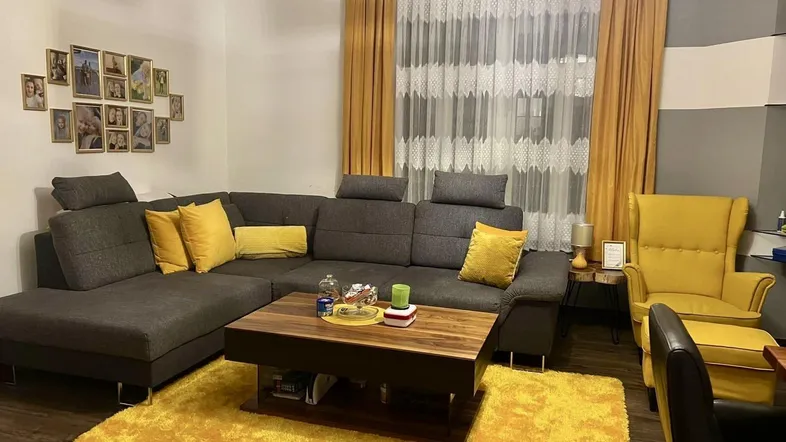 Gemütliches Wohnzimmer mit großem Ecksofa, gelben Akzenten und modernem Couchtisch.
