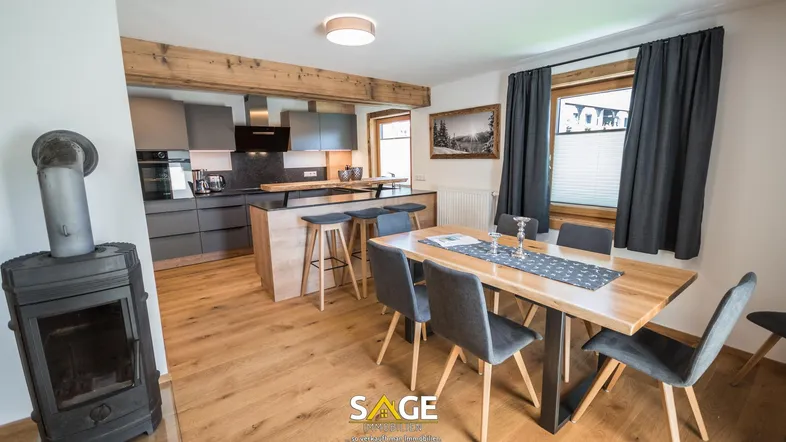 Gemütlicher Essbereich mit Holztisch und Stühlen, angrenzend an die moderne Küche mit Kochinsel.