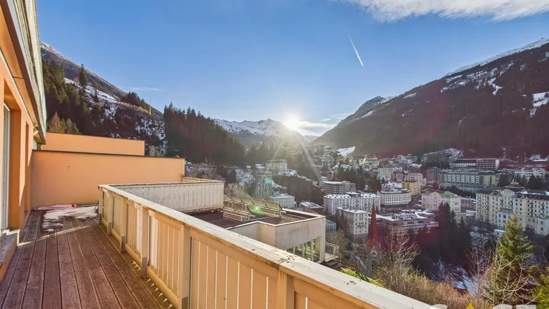 Geräumige Holzterrasse mit atemberaubendem Blick auf die verschneite Berglandschaft und die Stadt.