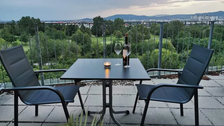 Gemütliche Terrasse mit Sitzgelegenheiten, Kerzenlicht und weitem Blick über die Stadt und Natur.
