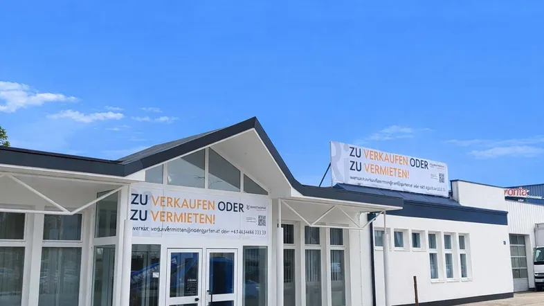 Modernes Geschäftsgebäude mit weißer Fassade und großen Fenstern unter blauem Himmel, bereit zum Verkauf oder zur Vermietung.
